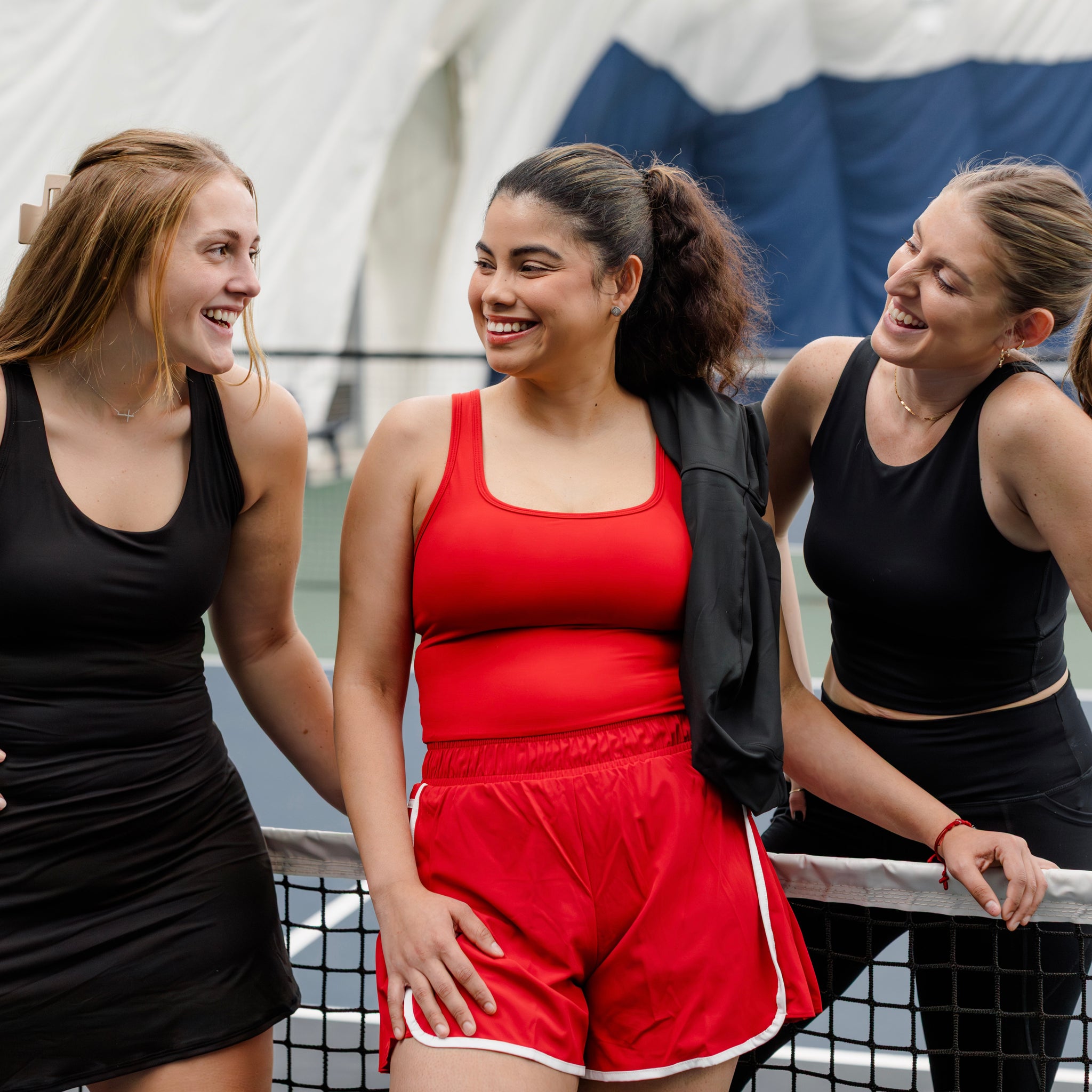 Woman wearing a red and white shortsie with two other friends on a pickleball court.