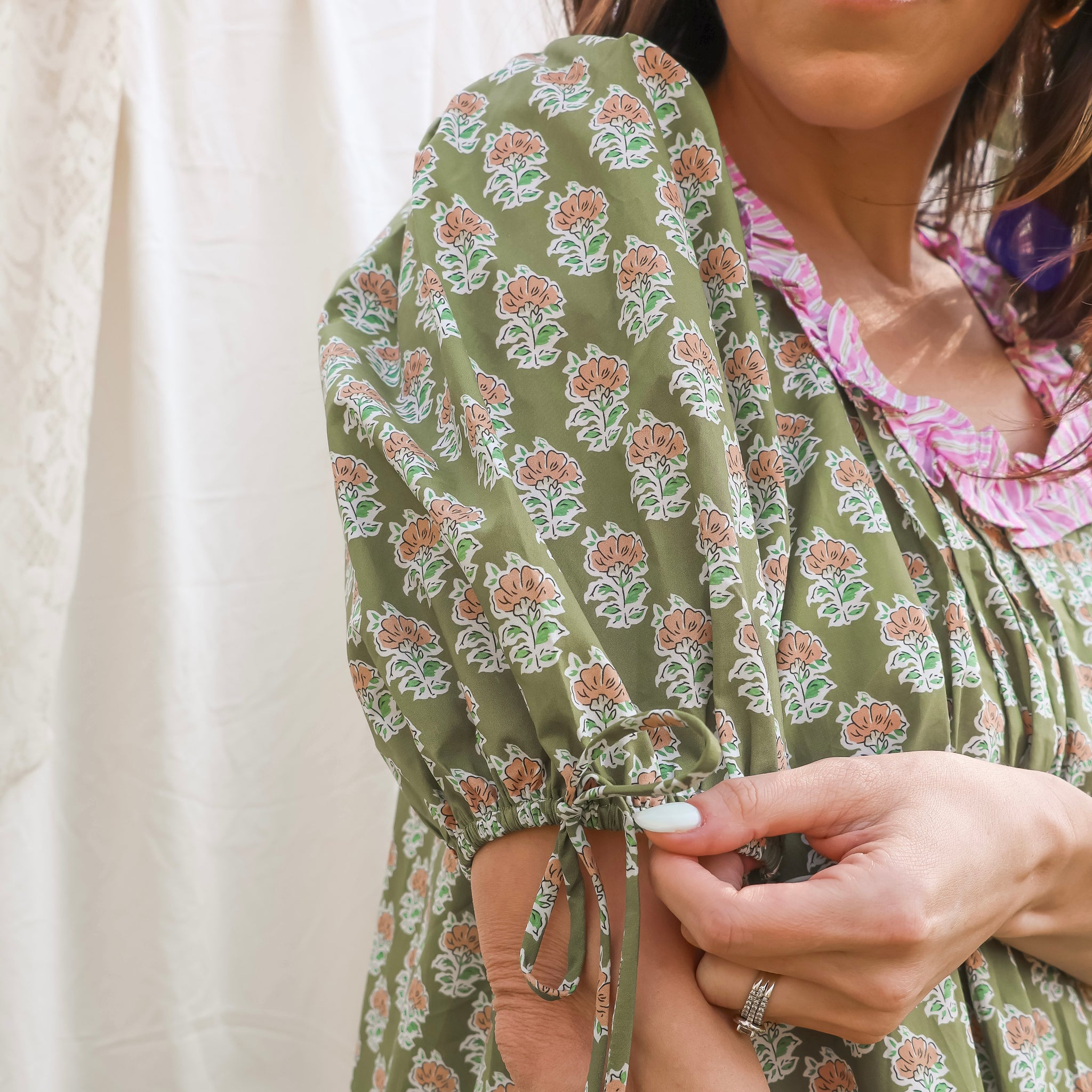 Woman wearing a green floral dress with a white background