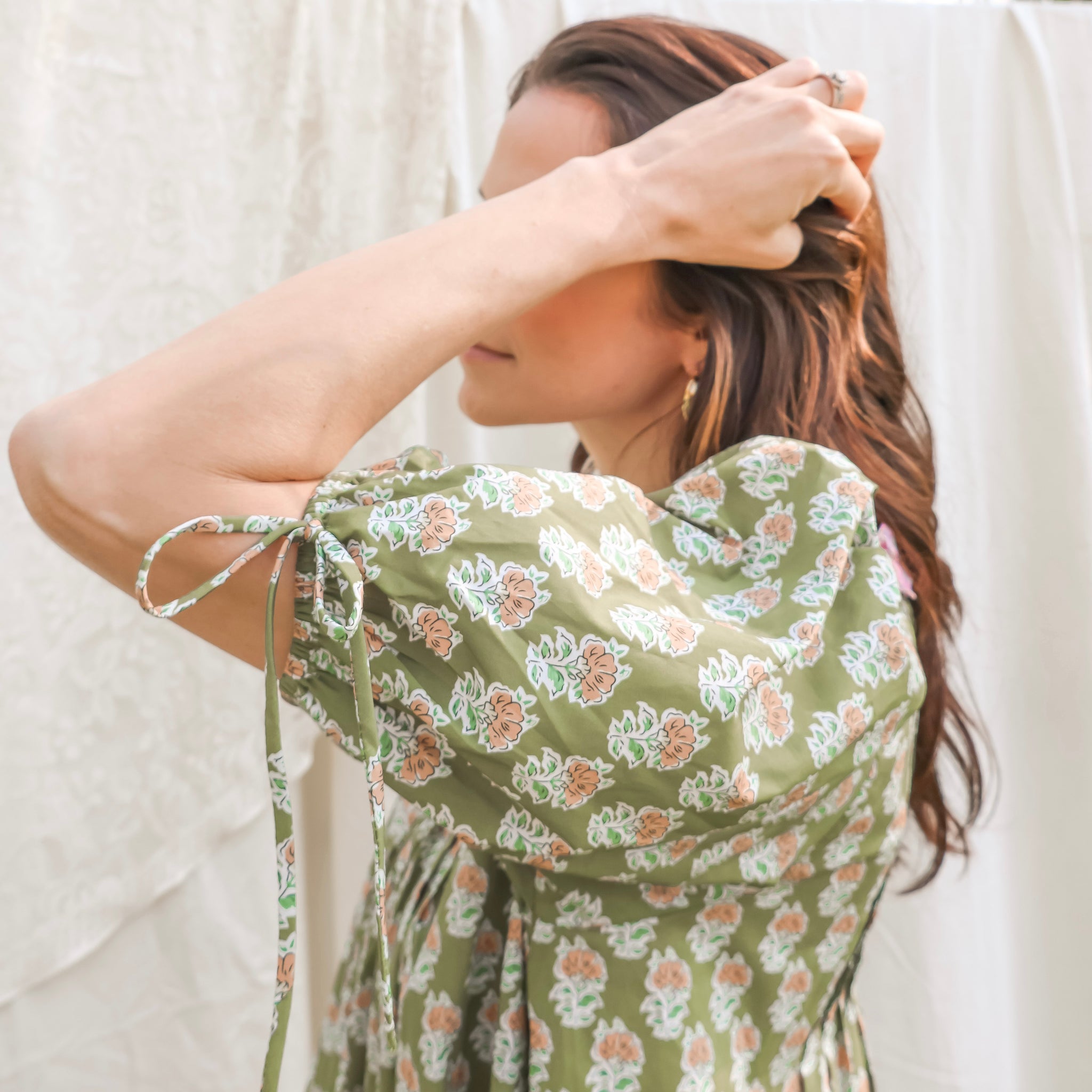 Woman wearing a green floral dress against a white background