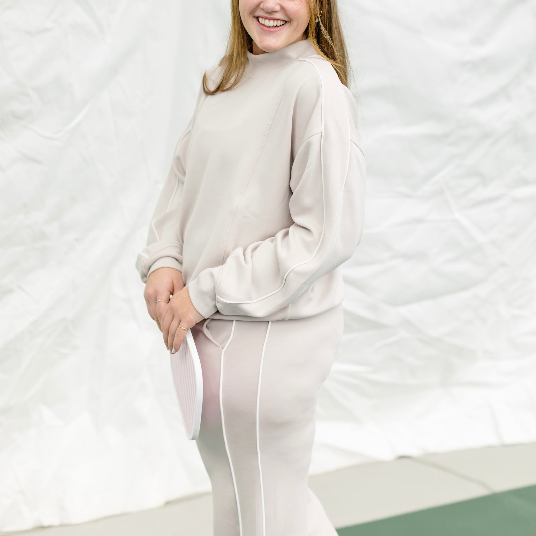 Person wearing a beige tracksuit against a white background