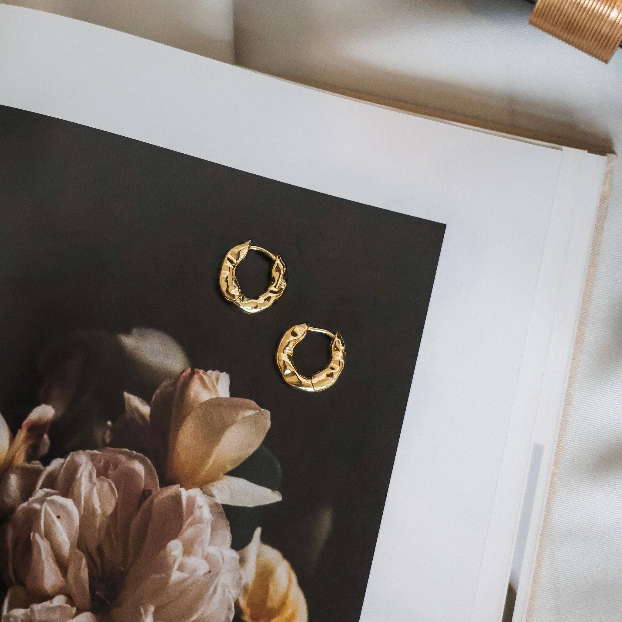 Gold hoop earrings on a magazine with floral design