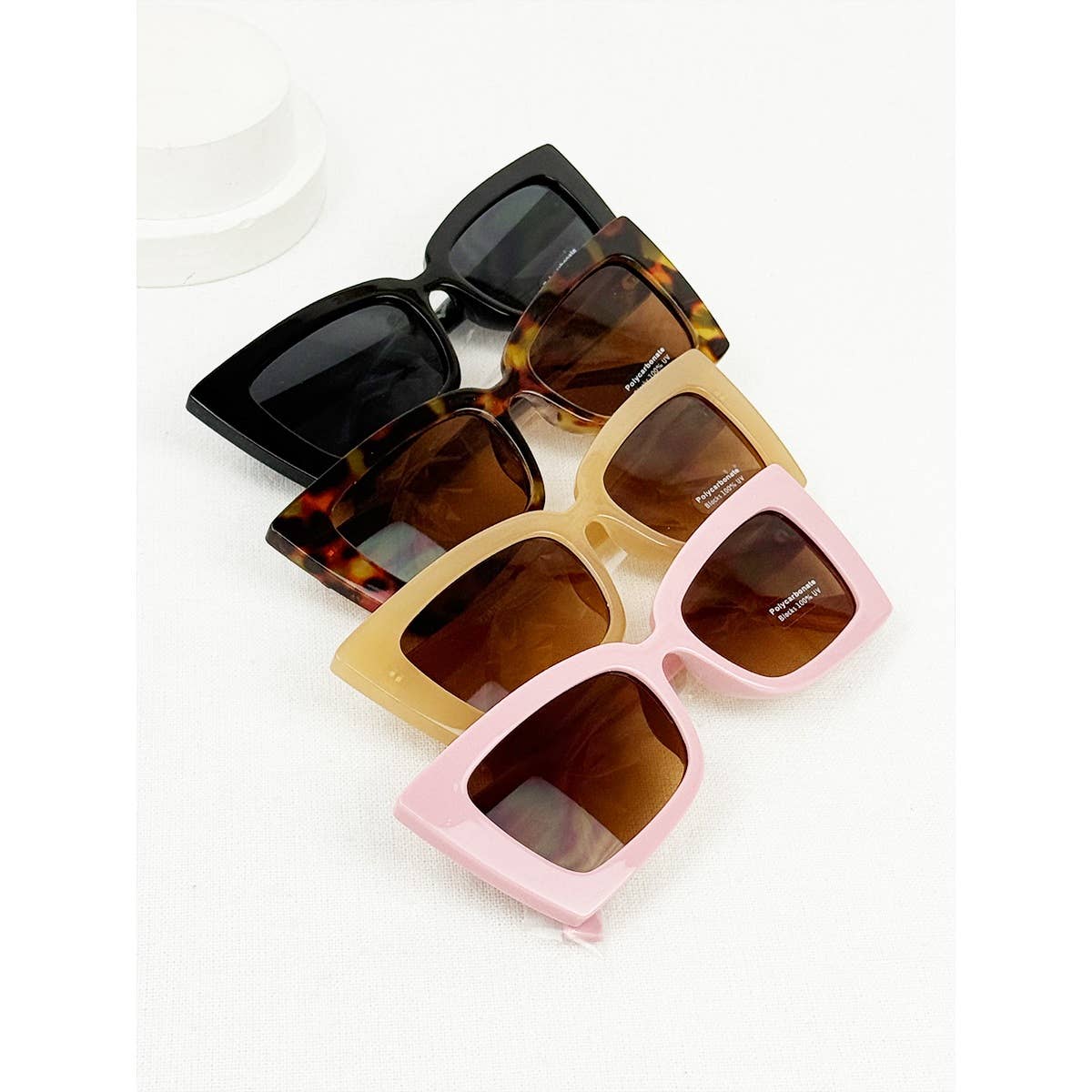Four pairs of sunglasses in different colors on a white background