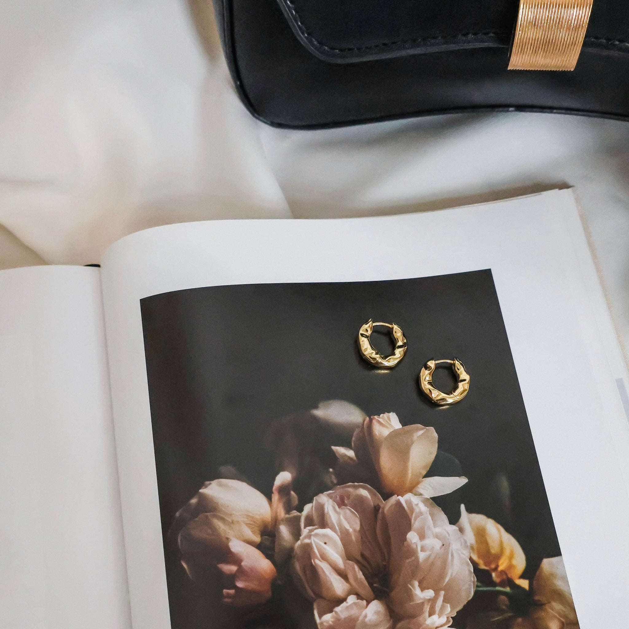 Gold hoop earrings on a magazine with flowers
