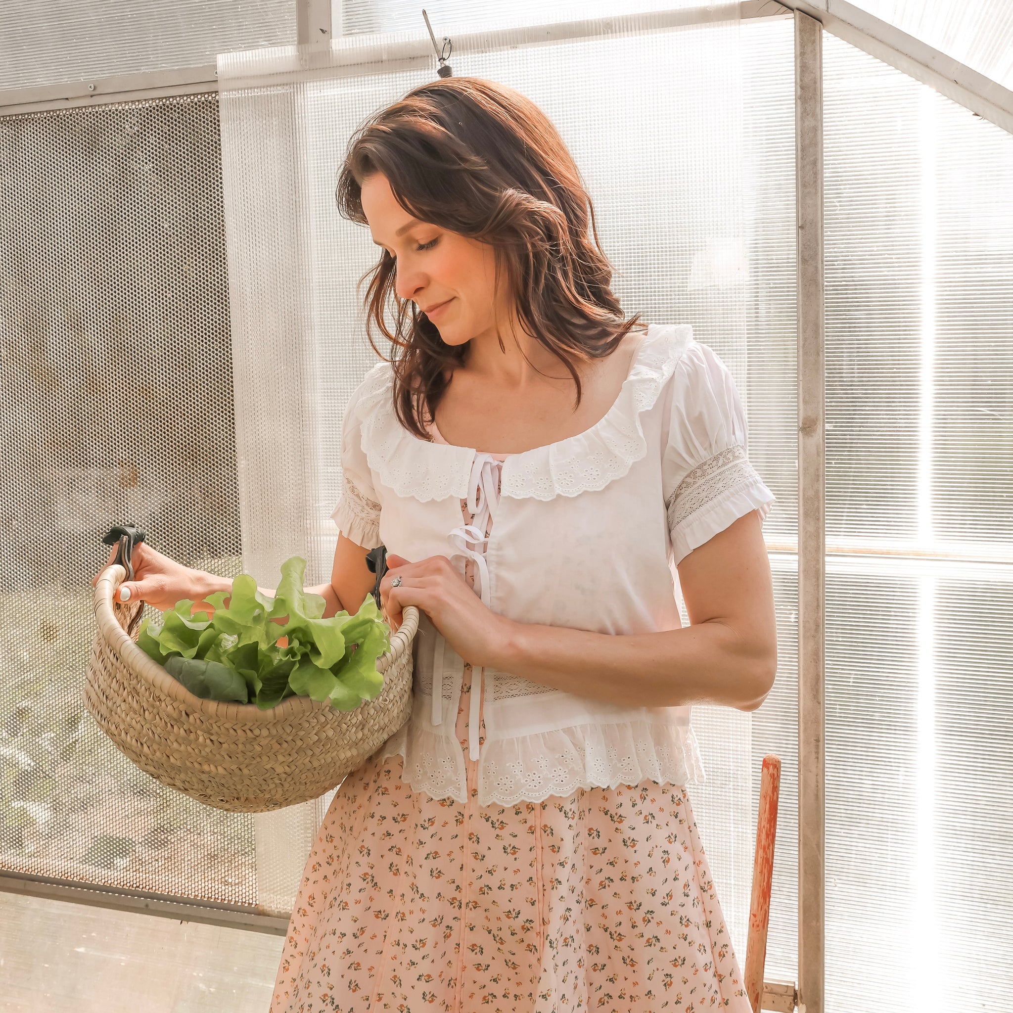 Woman holding a basket of fresh produce in a greenhouse