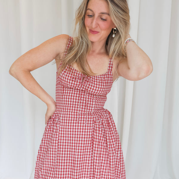 Woman wearing a red and white checkered dress against a plain background