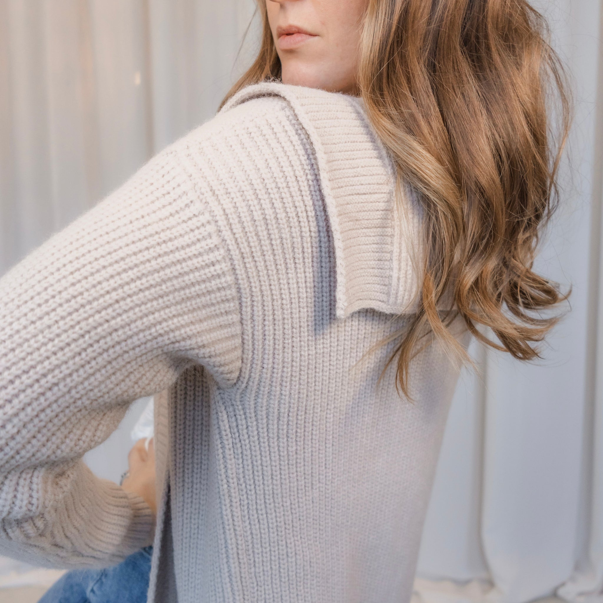 Woman wearing a beige knitted sweater with a blurred background