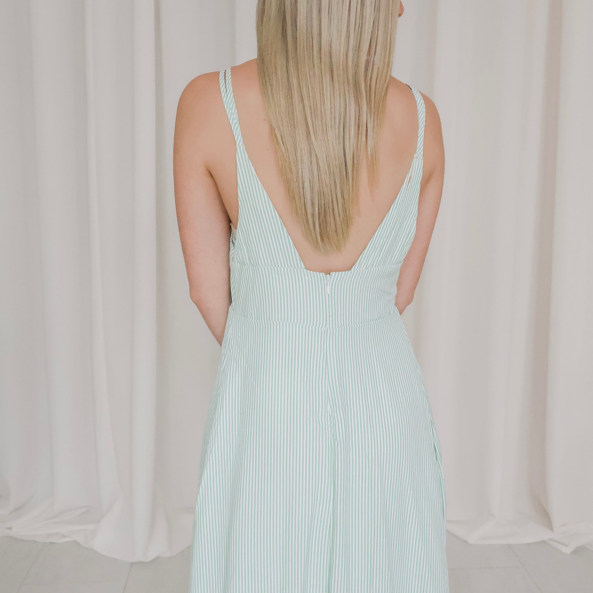 Woman wearing a light green sleeveless dress against a neutral background