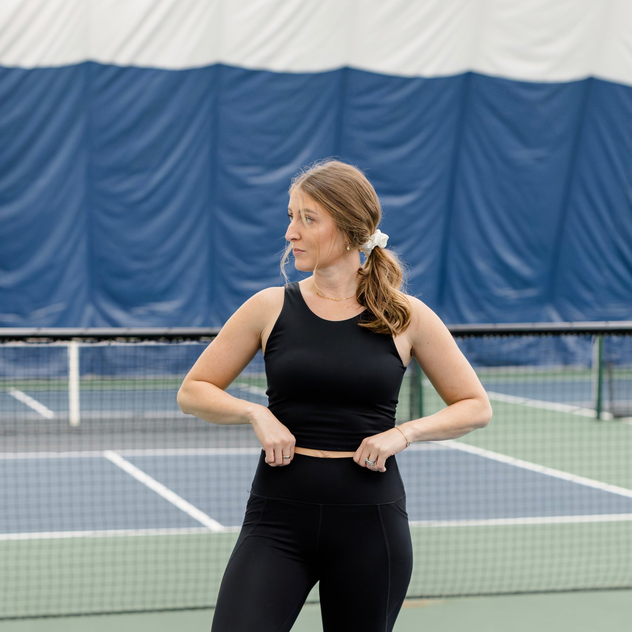 Woman wearing a black athletic set on a pickleball court. 