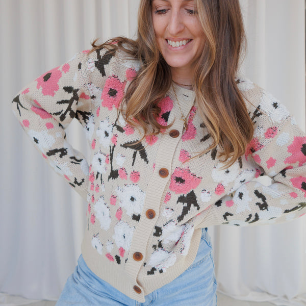 Woman wearing a floral cardigan with a neutral background