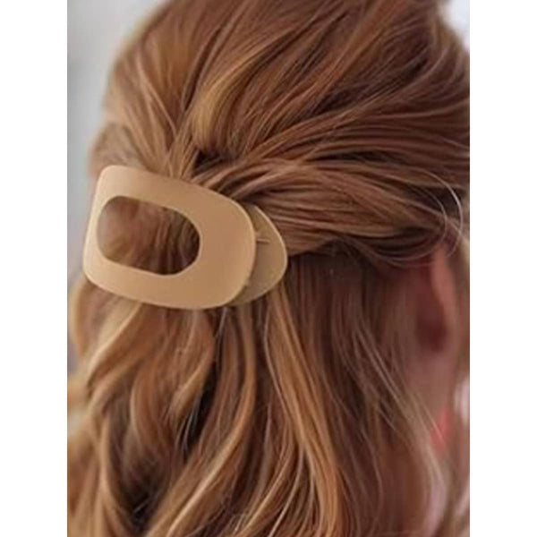 Beige hair clip on a person's hair with a neutral background