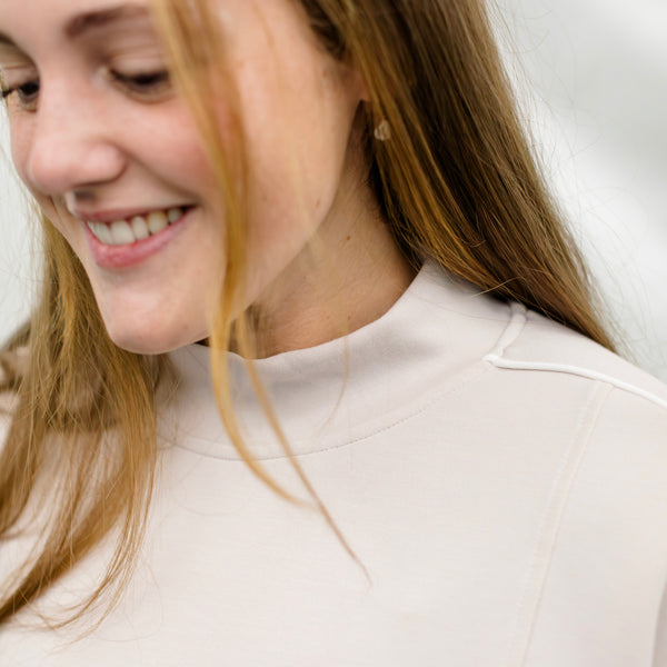 Woman wearing a beige track suit with white piping details.