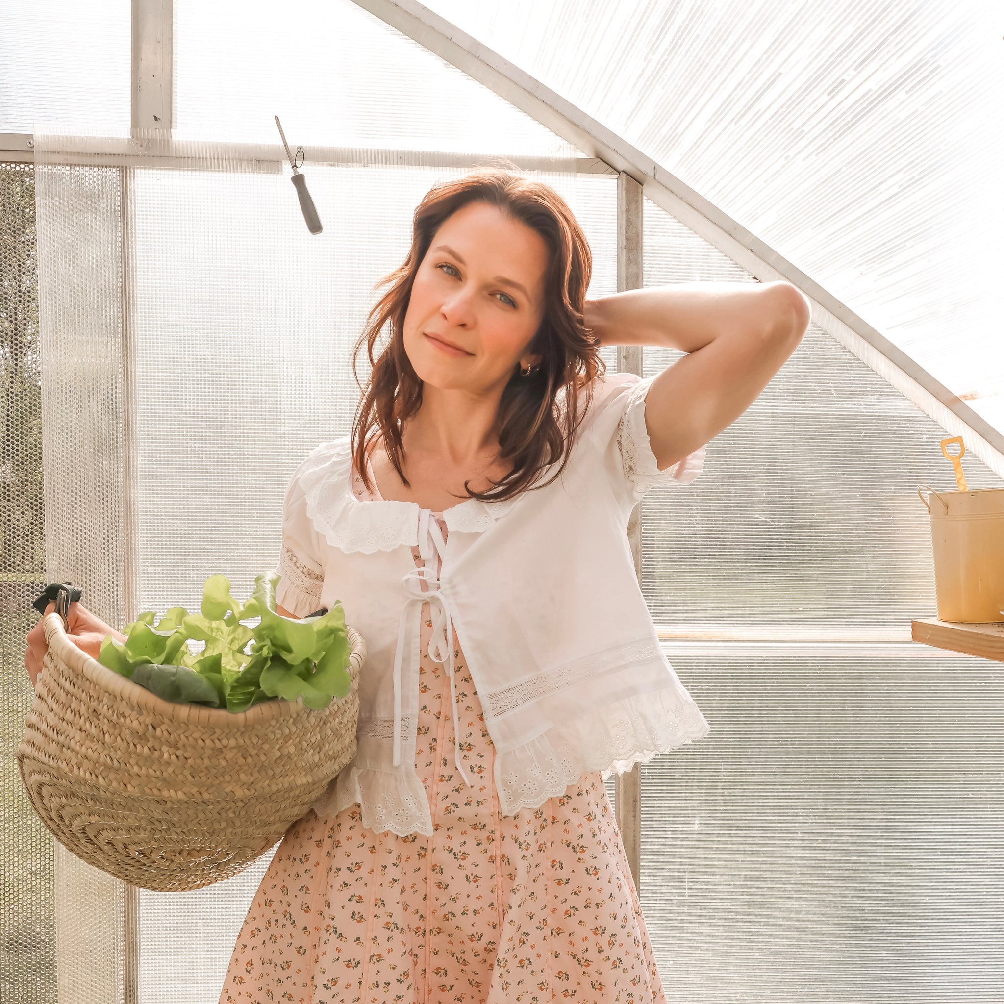 Woman holding a basket of greens in a greenhouse