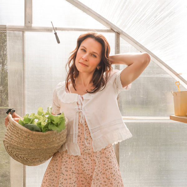 Woman holding a basket of greens in a greenhouse