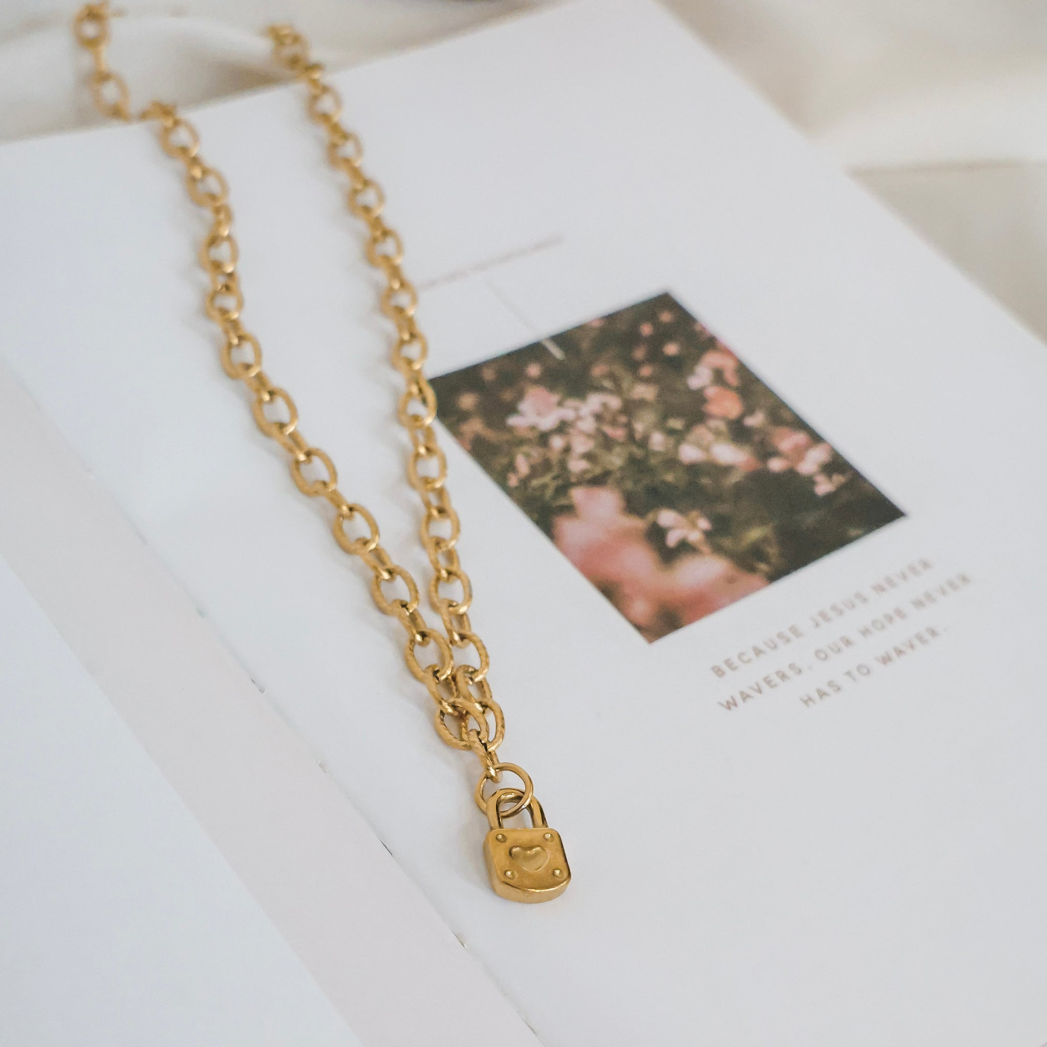 Gold chain necklace with a lock pendant on a book
