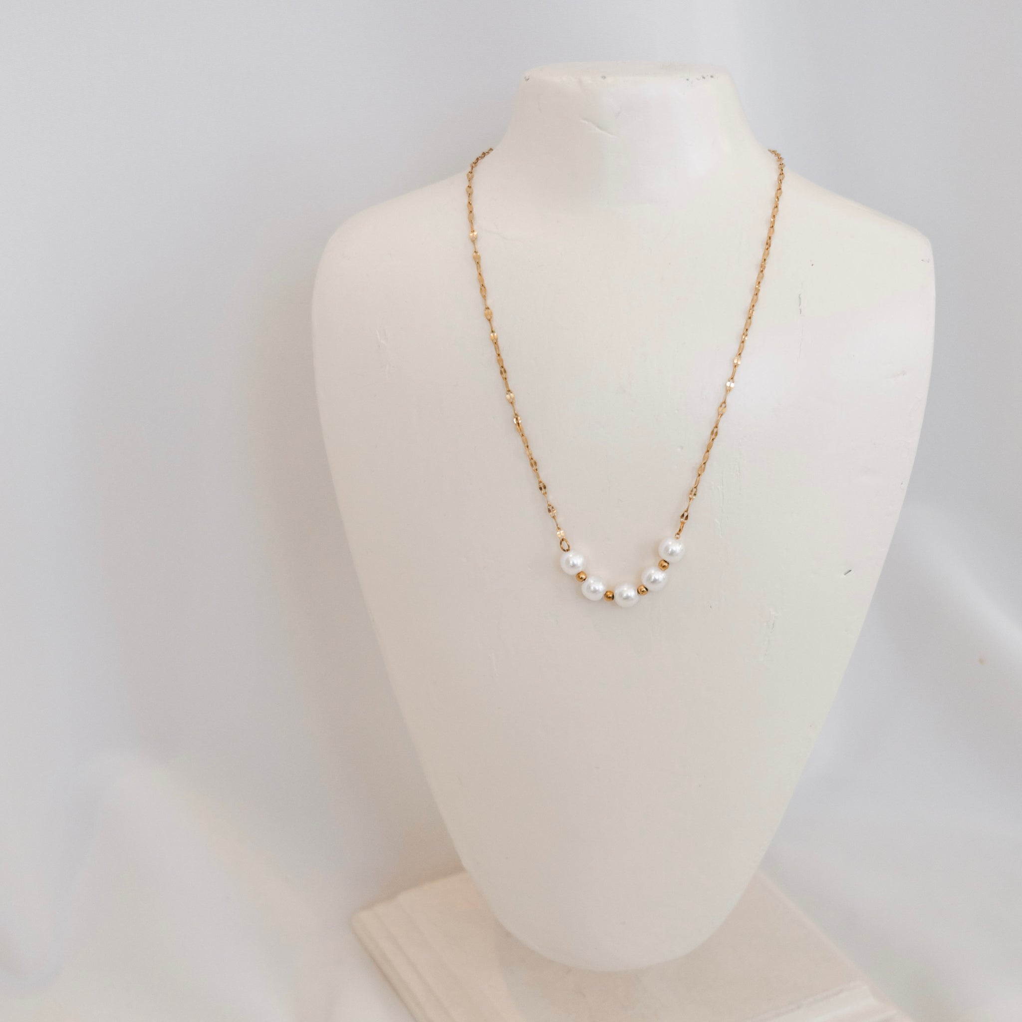 Pearl necklace on a mannequin bust against a white background