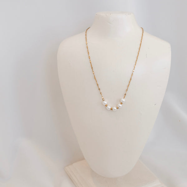 Pearl necklace on a mannequin bust against a white background