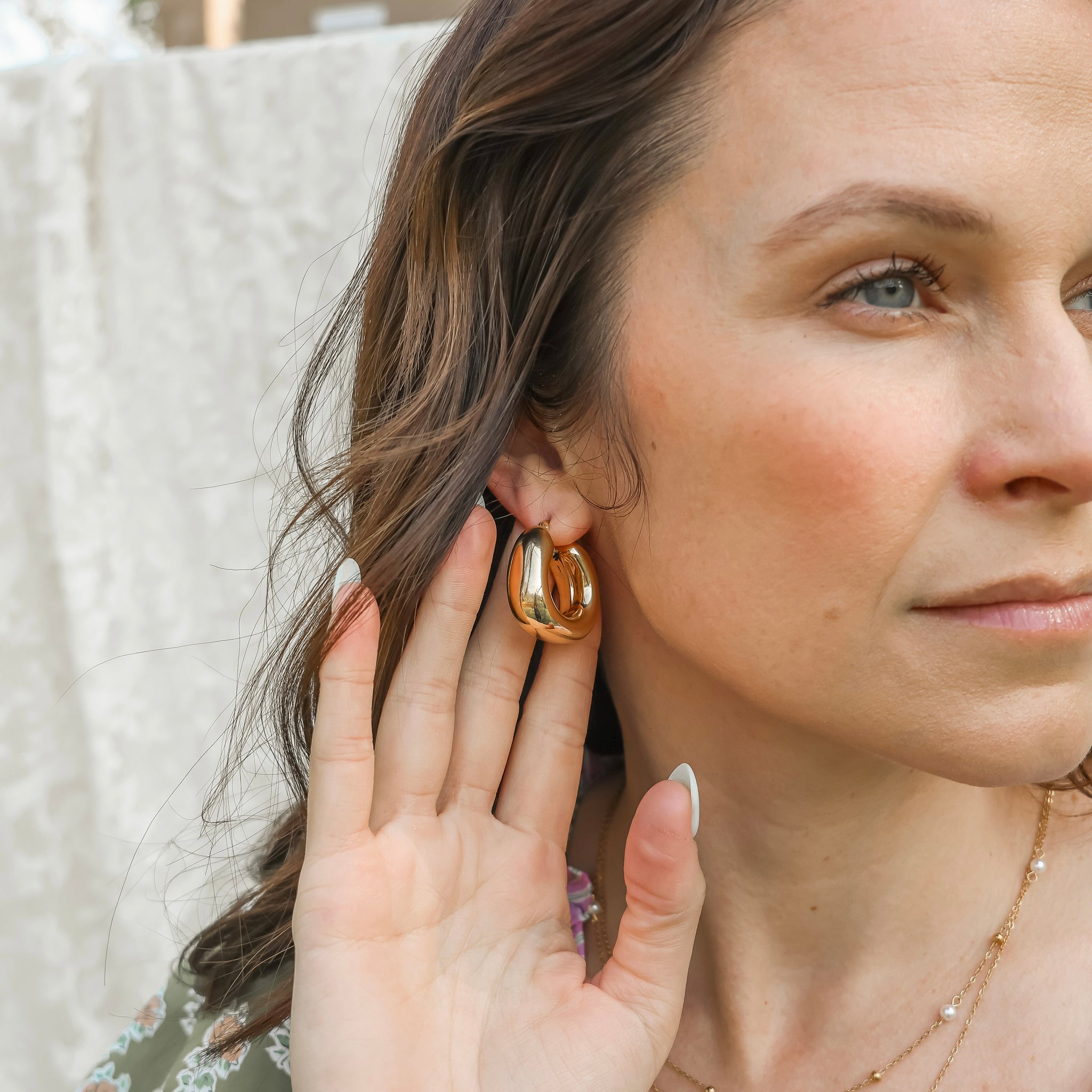 Woman wearing gold hoop earrings with a neutral background