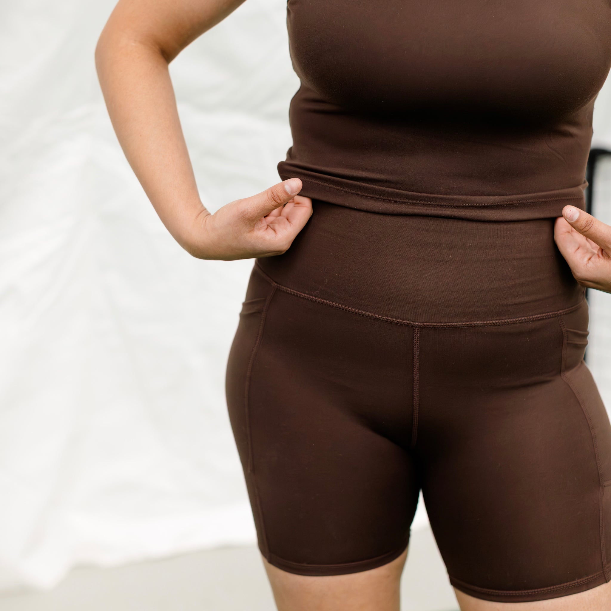 Woman wearing espresso colored athletic set showing the fabric.