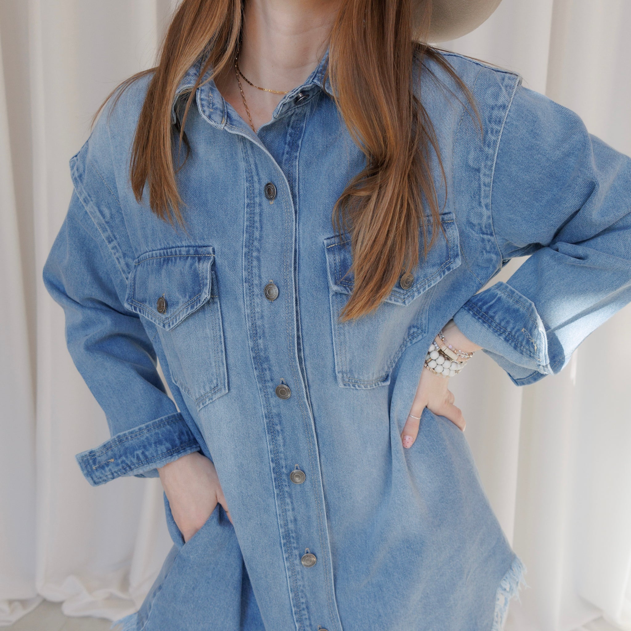 Person wearing a blue denim shirt  dress against a white background