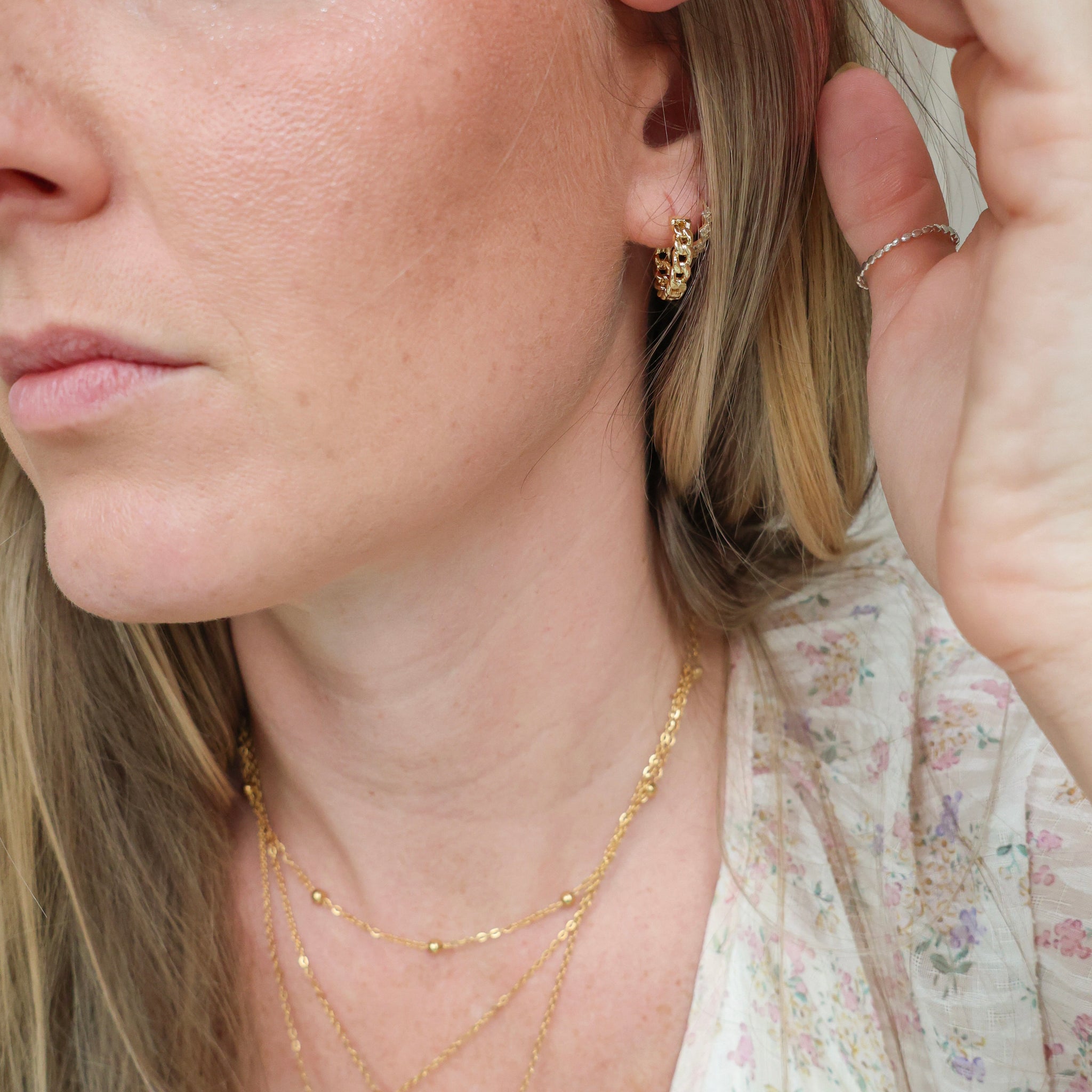 Close-up of a woman wearing gold hoop earrings and necklaces.