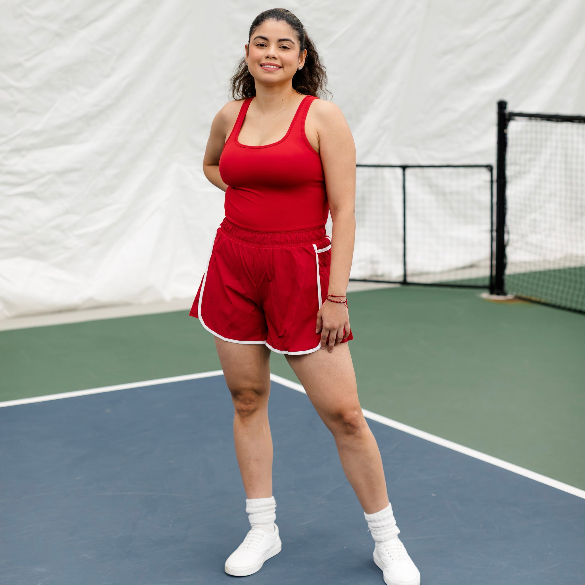 Woman wearing a red and white shortsie while standing on a pickleball court.