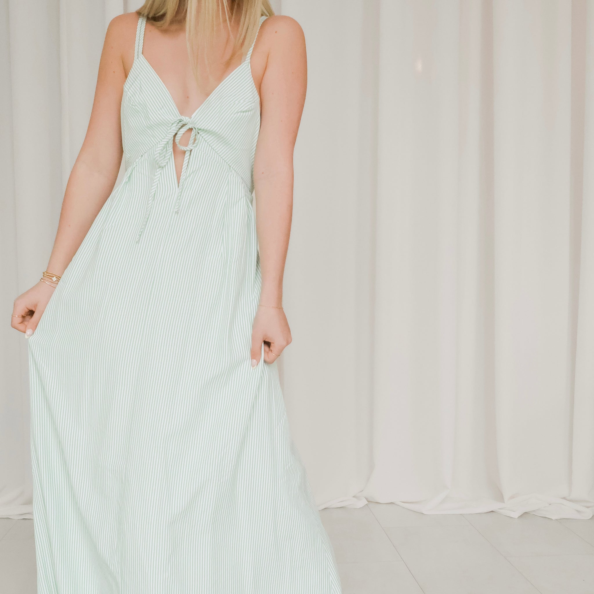 Woman wearing a white dress with thin straps against a plain background