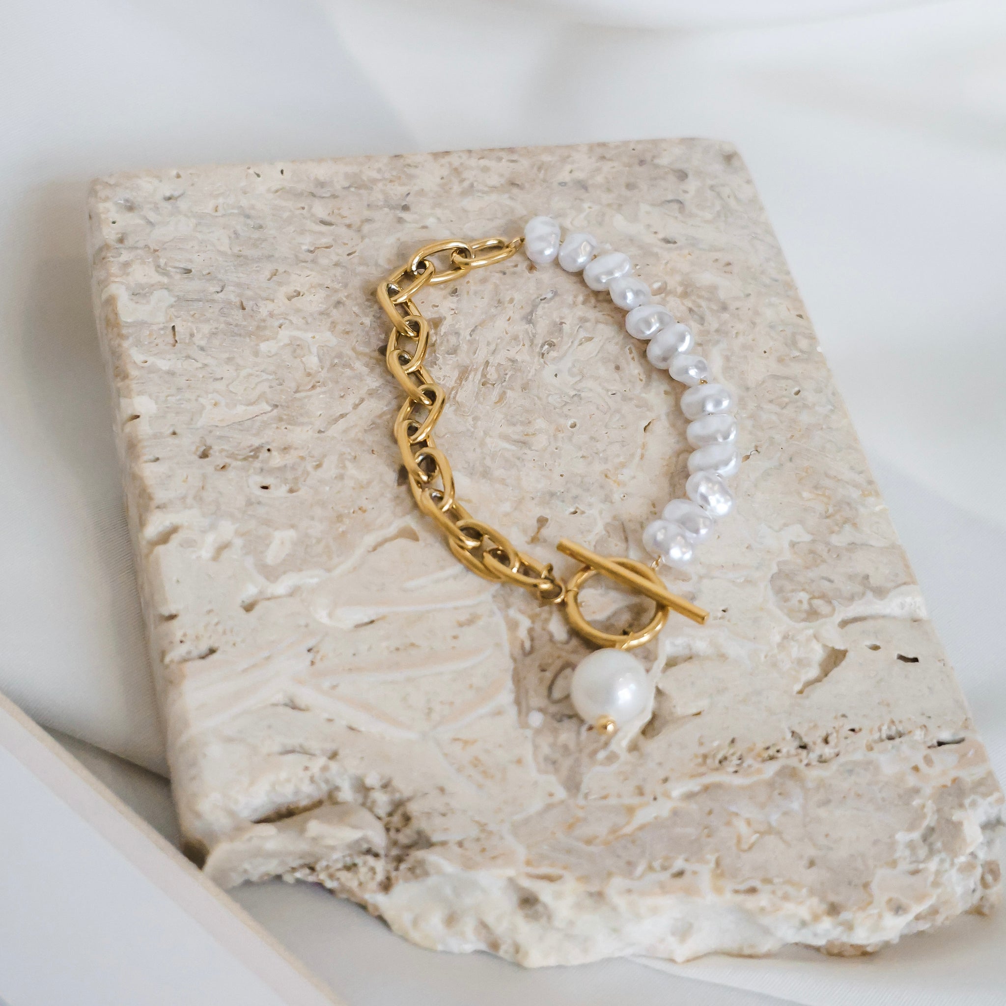 Pearl and gold bracelet on a stone surface