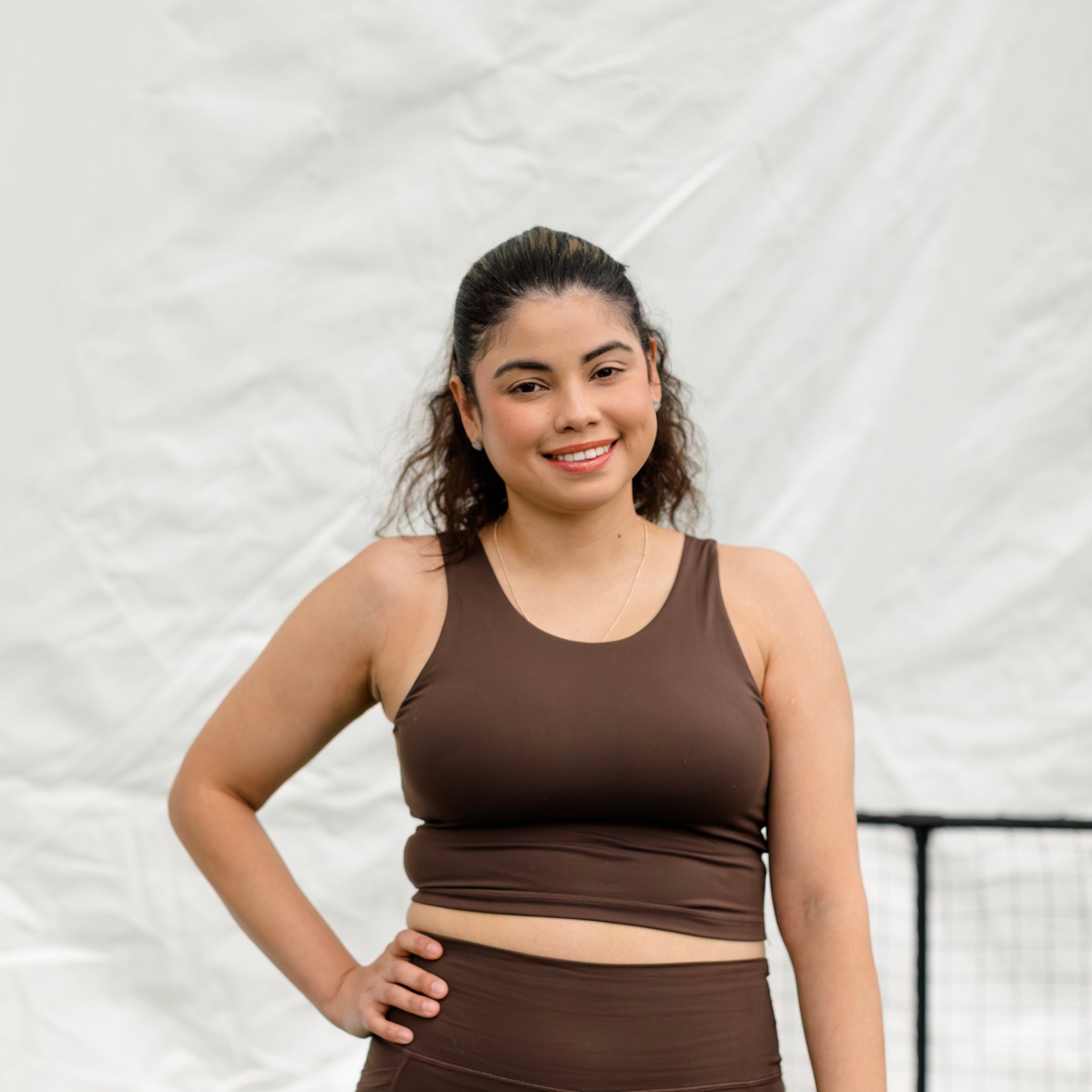 Woman wearing an espresso colored  athletic set on a pickleball court. 