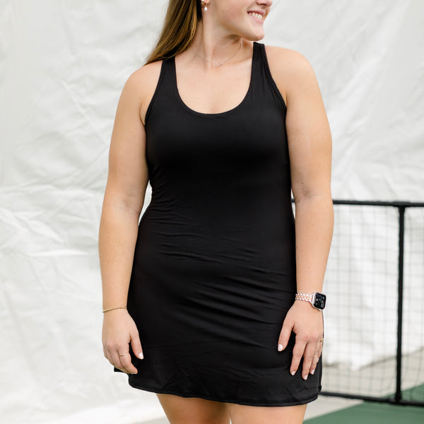 Woman wearing black athletic dress on a pickleball court.