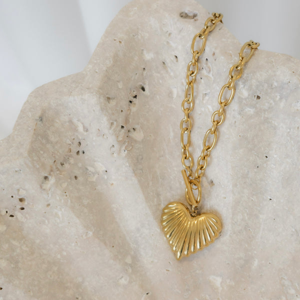Gold heart-shaped pendant necklace on a textured stone surface
